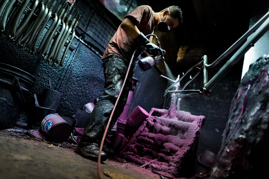 A bicycle painter, holding a spray gun, paints a bike frame in a paint booth of a small scale bicycle factory in Bogota, Colombia.