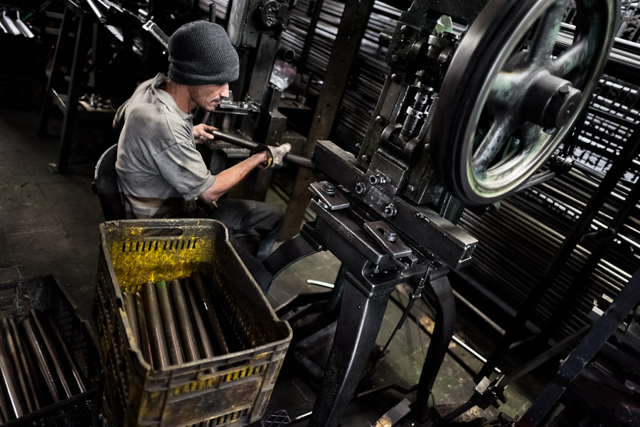 A bicycle worker works on a tube bender machine in a small scale bicycle factory in Bogota, Colombia.