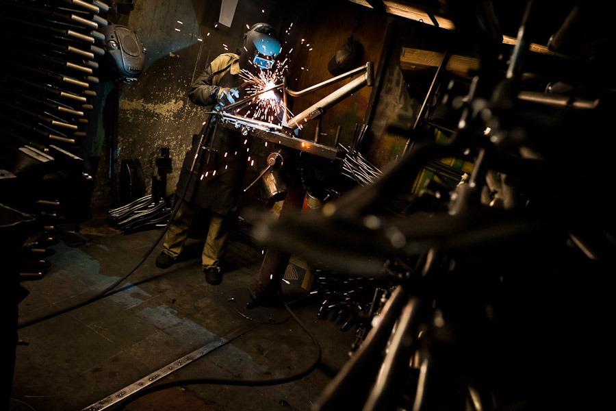 A bicycle welder works on a bike frame fixed on a welding jig in a small scale bicycle factory in Bogota, Colombia.