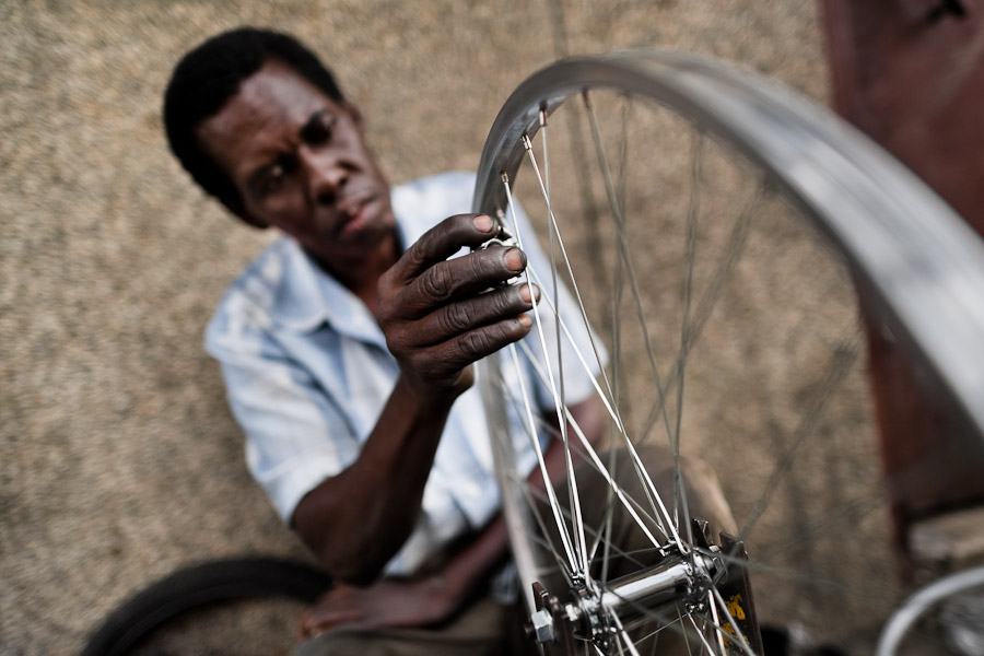 A bicycle mechanic works with a spoke wrench on bicycle wheel outside a small scale bicycle factory in Cali, Colombia.