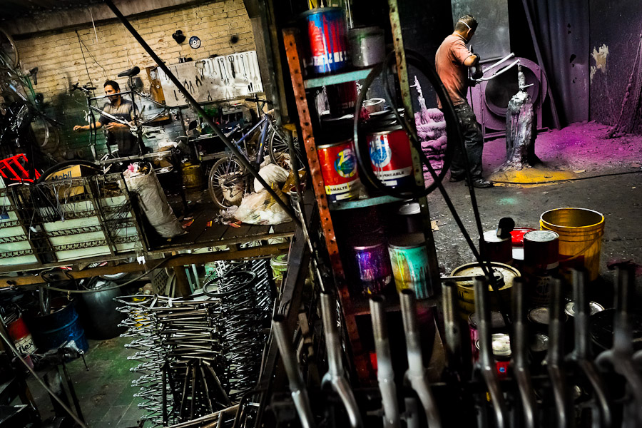 A bicycle painter and a bicycle mechanic are seen working in a small scale bicycle factory in Bogota, Colombia.