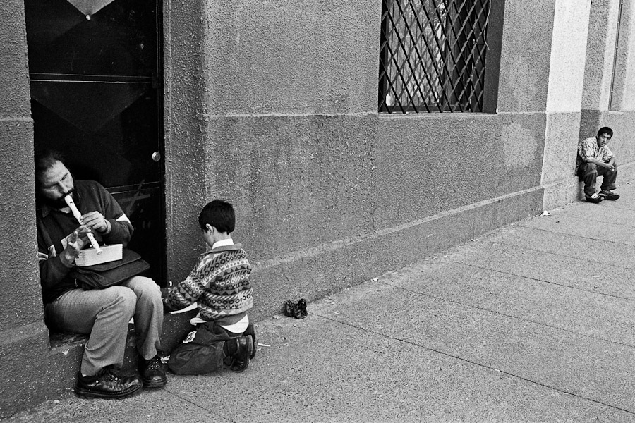 A blind man, accompanied by his son, plays flute on the street of Santiago de Chile, Chile.
