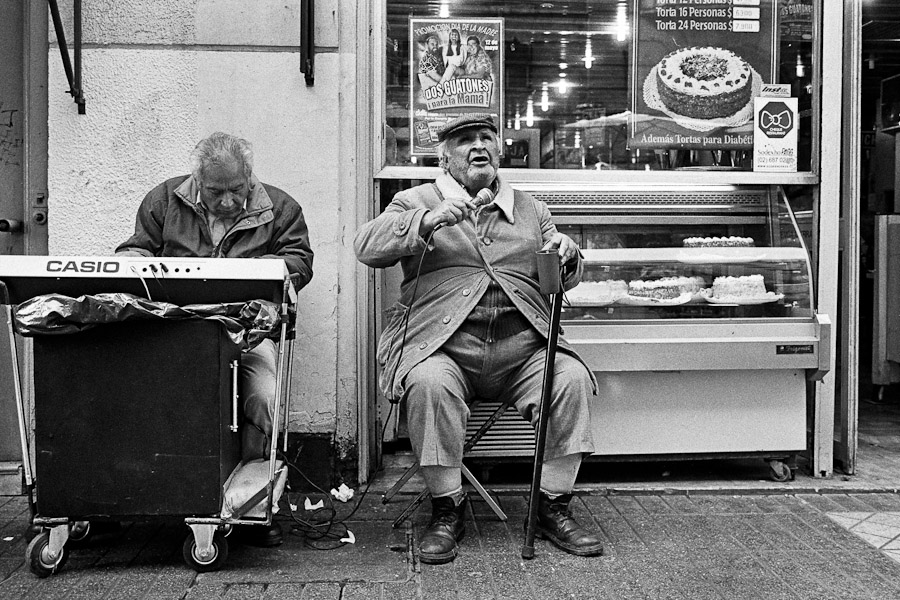 A blind man, accompanied by his fellow musician, earns money by singing on the street of Santiago de Chile, Chile.