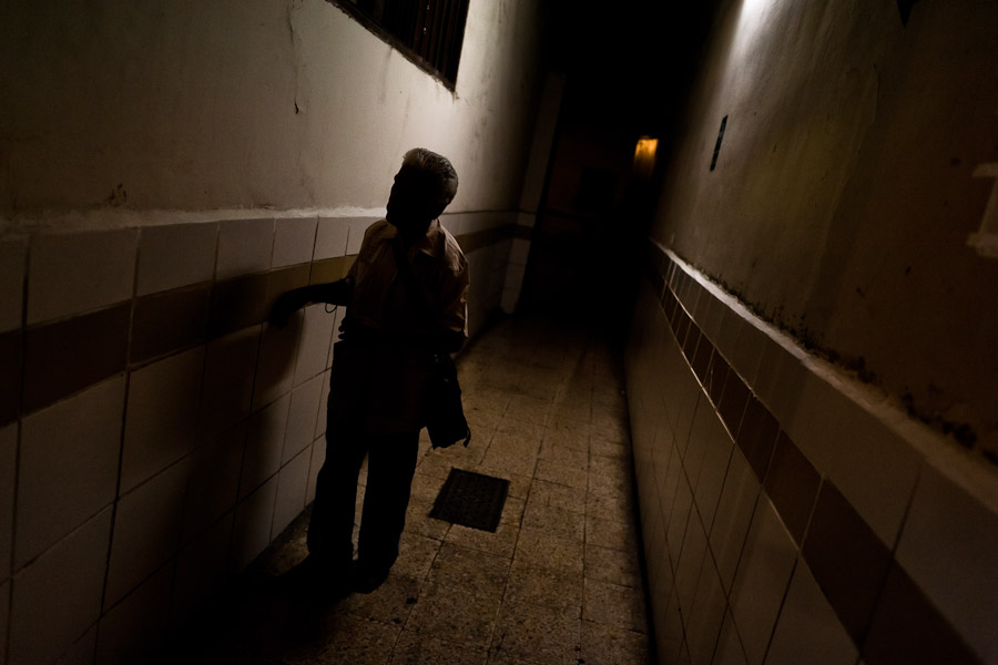 A blind man, touching the wall, finds his way in the corridor of Unión Nacional de Ciegos del Perú, a social club for the visually impaired in Lima, Peru.