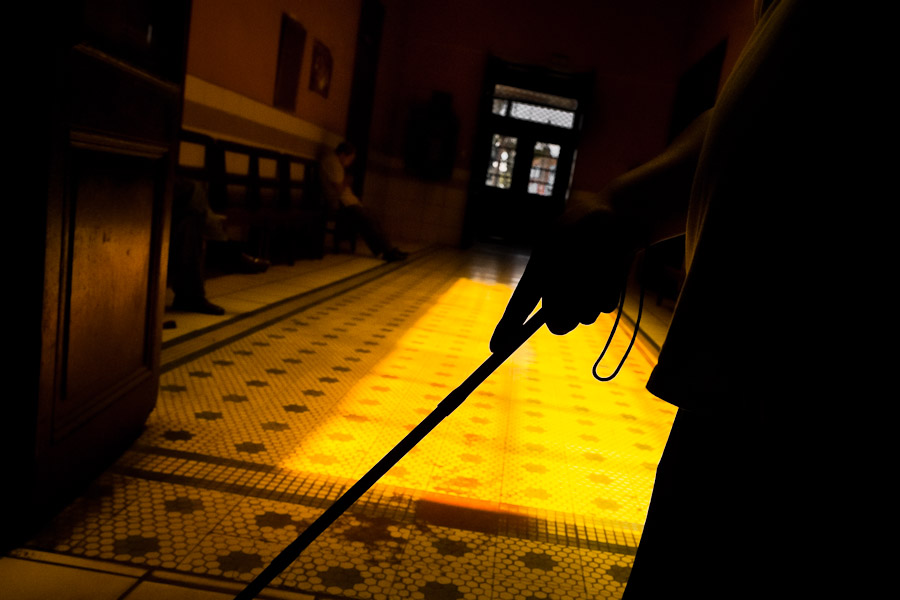 A blind man, using a white cane, finds his way in the foyer of Unión Nacional de Ciegos del Perú, a social club for the visually impaired in Lima, Peru.