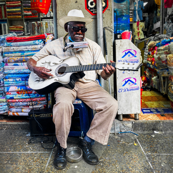 A Colombian blind musician earns money by playing guitar and singing in the street in Medellín, Colombia.