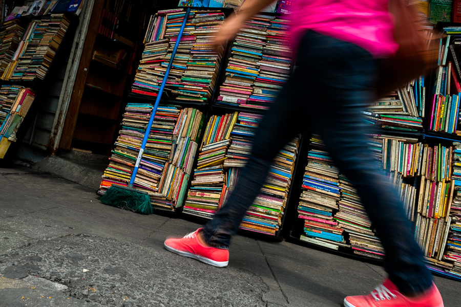 A Salvadoran woman walks along hundreds of used books stacked in boxes on the street in a secondhand bookshop in San Salvador, El Salvador.