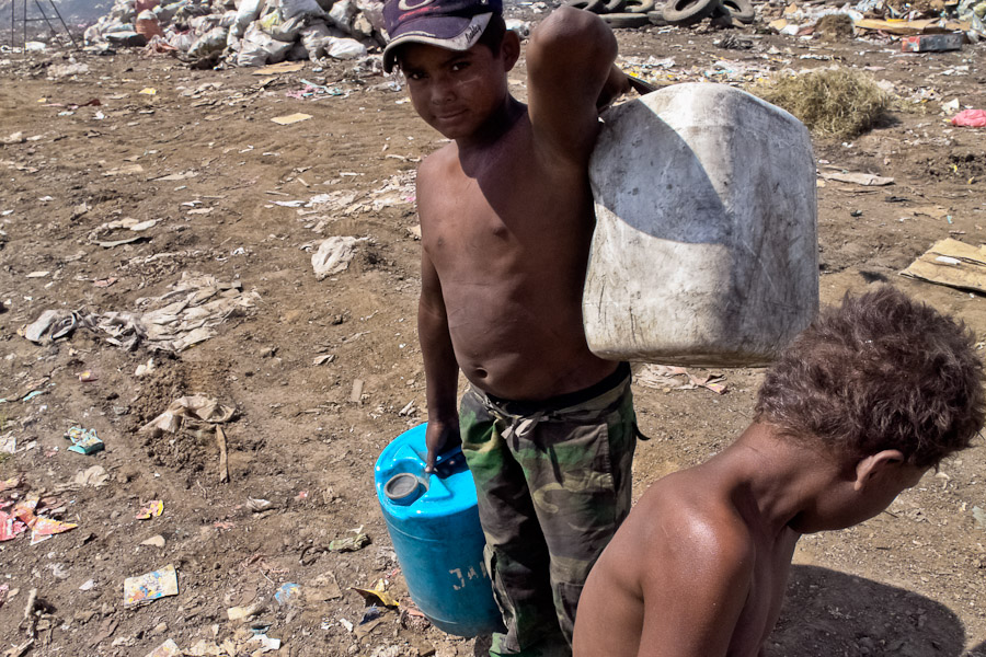 A young boy carrying barrels of contaminated water. There is a neighbourhood of about 200 families which is situated right inside the area of the La Chureca garbage dump.