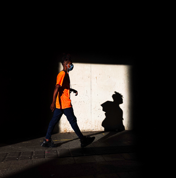 An Afro-Colombian boy with a mask walks in the street near San Antonio Metro station in Medellín, Colombia.