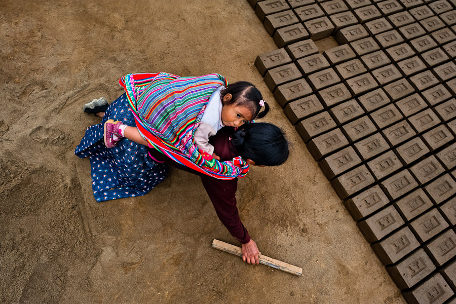 A Peruvian indigenous woman, carrying a baby on her back, works at a brick factory in Huachipa, a suburb in the outskirts of Lima, Peru.