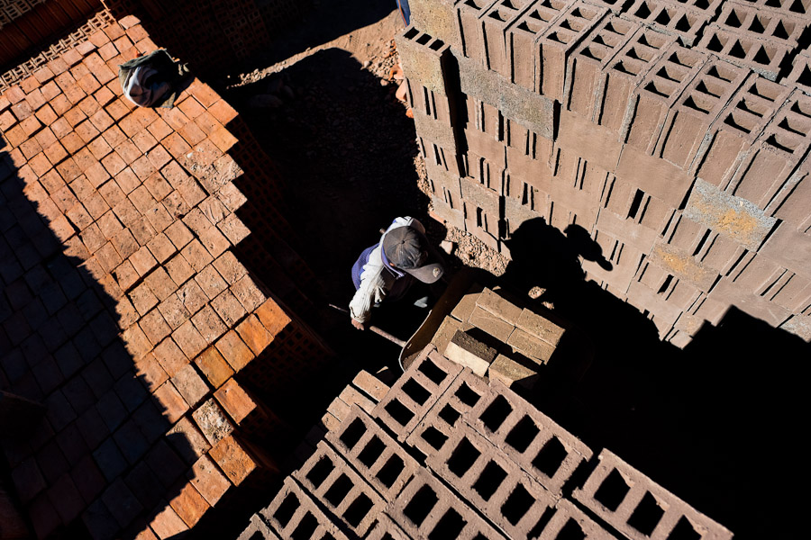 A Peruvian boy pushes a wheelbarrow, loaded with bricks, at a brick factory in the outskirts of Puno, Peru.