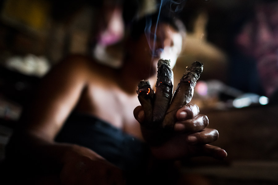 A Colombian woman shows three burning cigars while predicting the future from shapes shown on the tobacco leaves in a shaman's house in Cali, Colombia.