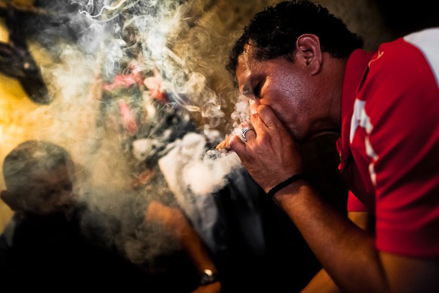 A Salvadorean ‘brujo’ (sorcerer) puffs a cigar to predict the future of his client from burn tobacco leaves in a street fortune telling shop in San Salvador, El Salvador.