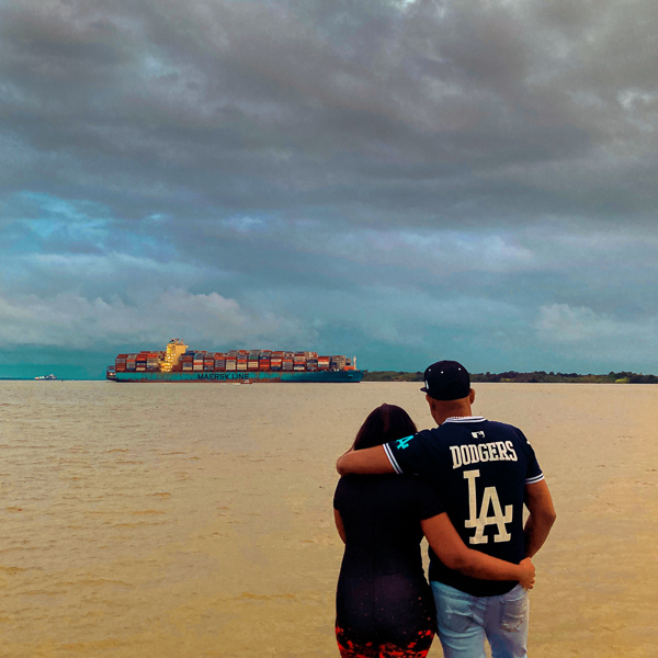A Colombian couple watches a huge cargo ship navigating to the Pacific port of Buenaventura, Colombia.