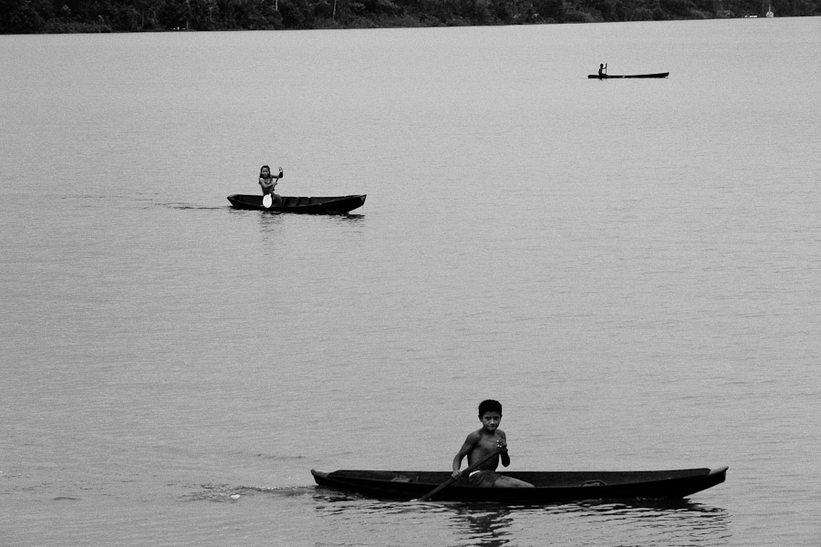 Indian kids from Amazonia paddle in their one-person dugout canoe on the Amazon river.