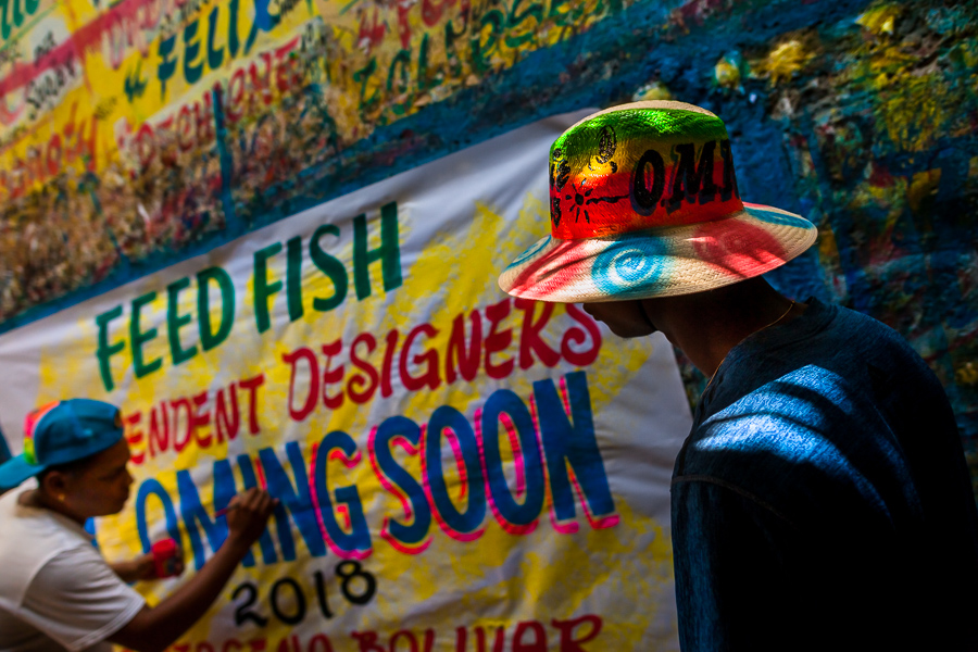 A Colombian sign painter paints letters on a hand-painted promotional banner in the sign painting workshop in Cartagena, Colombia.