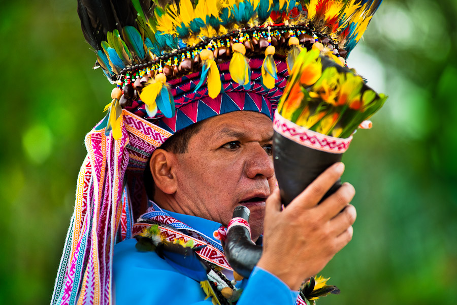 A shaman from the Kamentsá tribe, wearing a colorful feather headgear, plays horn trumpet during the Carnival of Forgiveness, a traditional indigenous celebration in Sibundoy, Colombia.