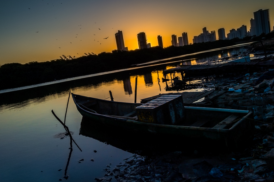 A rustic, low social class fisherman’s boat is seen anchored on the shore of the sea lagoon in Bahía de Manga, a luxurious neighborhood of Cartagena, Colombia.