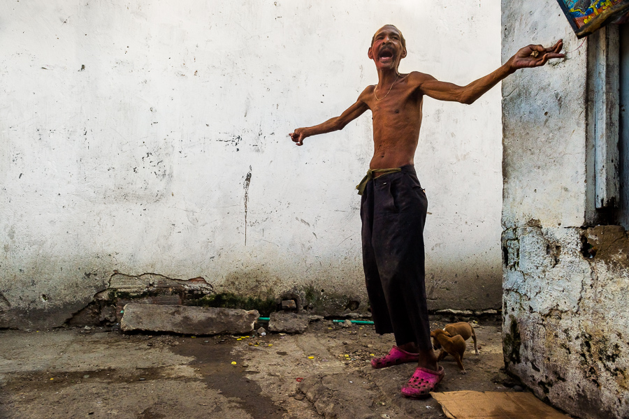 An Afro-Colombian man with a mental health disability argues with an imaginary person in a back street in Cartagena, Colombia.