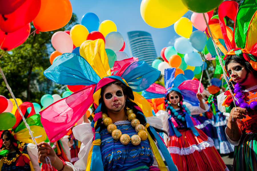 Mexican girls, wearing colorful costumes and having their faces painted, walk on the street during the Day of the Dead festival in Mexico City, Mexico.
