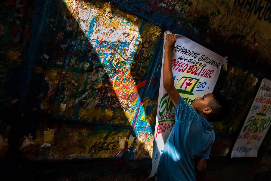 A Colombian sign painter apprentice takes down a just-finished music party poster in the sign painting workshop in Cartagena, Colombia.