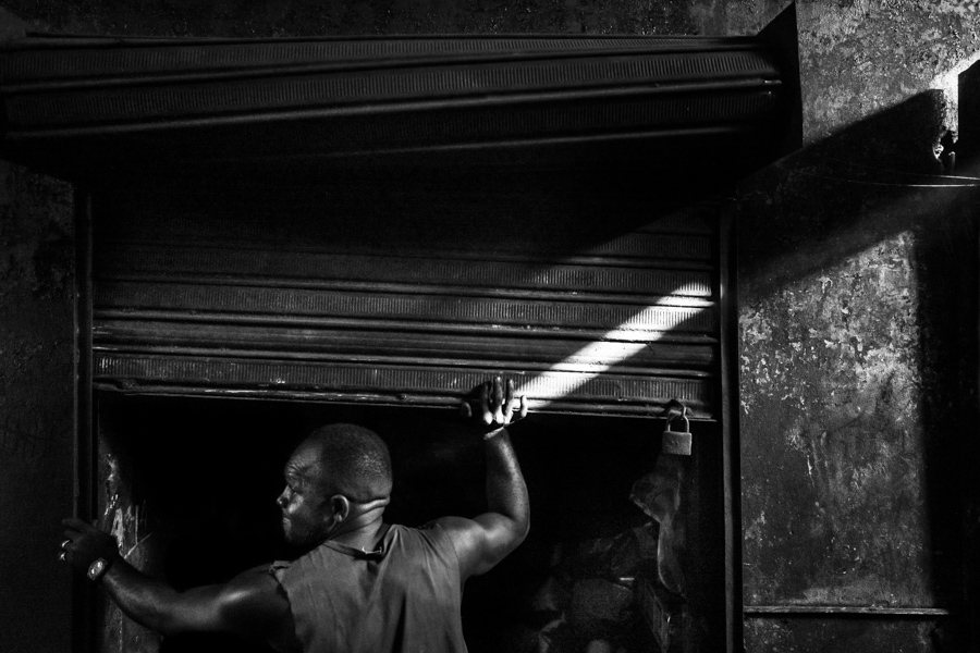 An Afro-Colombian charcoal worker opens a storage room in a street market in Cartagena, Colombia.