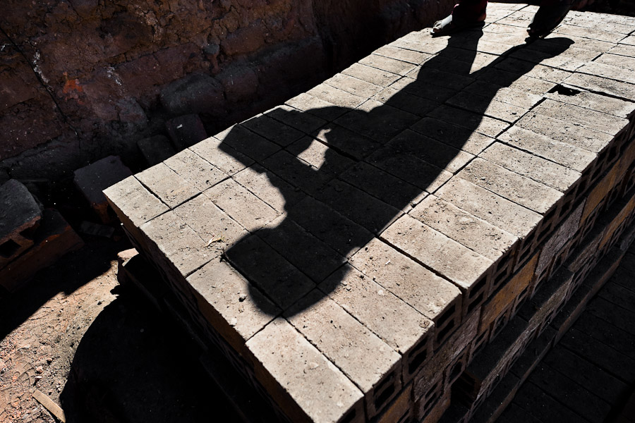A shadow of a working child is seen on a pile of bricks at a brick factory in the outskirts of Puno, Peru.