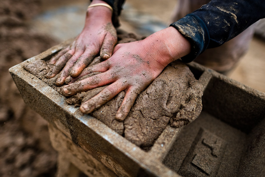 A Peruvian boy fills a wooden mold with clay for brick making at a brick factory in Huachipa, a suburb in the outskirts of Lima, Peru.