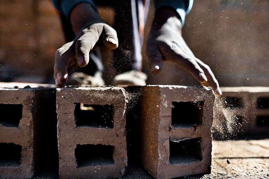 A Peruvian boy turns raw bricks for drying at a brick factory in the outskirts of Puno, Peru.