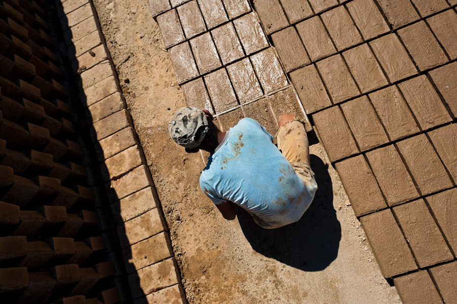 Moisés, a thirteen-year-old Salvadoran boy, molds bricks of clay at a brick factory in Istahua, El Salvador.