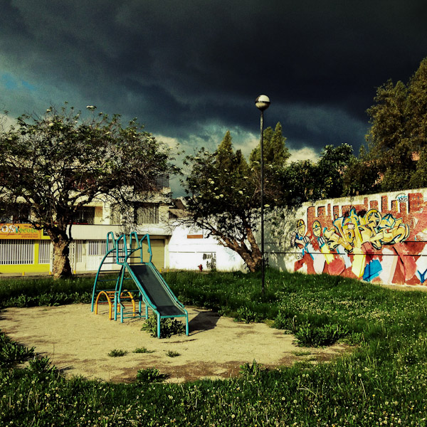 A children's slide is seen at the playground while a usual afternoon storm approaches in Quito, Ecuador.