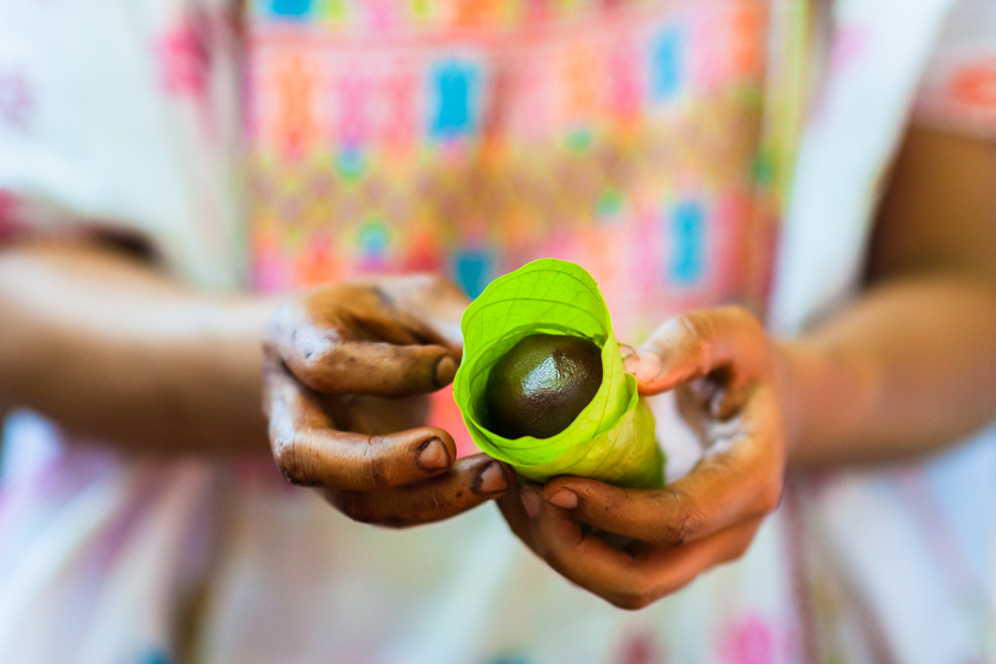 An Amuzgo indigenous woman wraps a chocolate ball made of raw cacao paste into a cacao tree leaf in artisanal chocolate manufacture in Xochistlahuaca, Guerrero, Mexico.