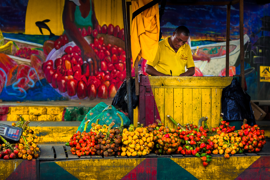 An Afro-Colombian street vendor sells raw chontaduro (peach palm) fruits under the highway bridge in Cali, Valle del Cauca, Colombia.