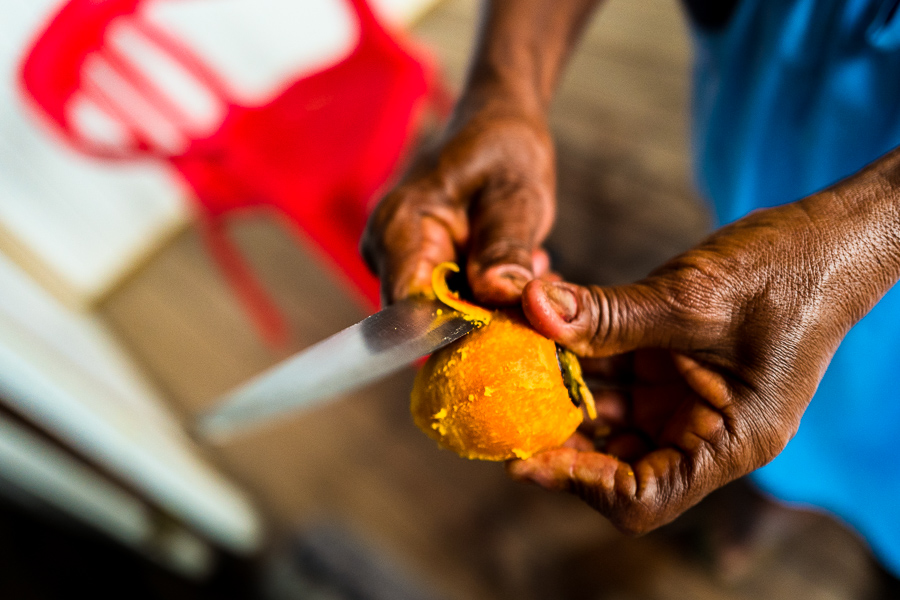 An Afro-Colombian woman peels a freshly cooked chontaduro (peach palm) fruit with a knife on the porch of her house in Quibdó, Chocó, Colombia.