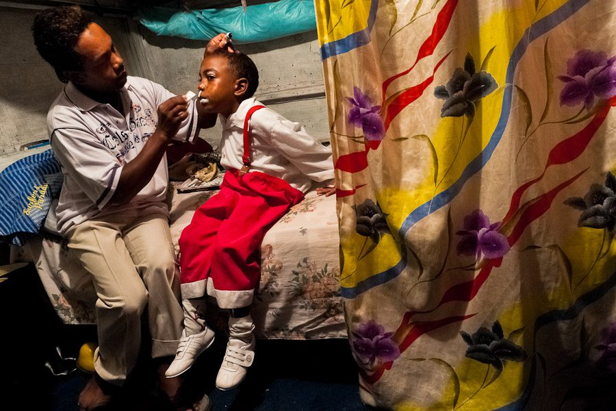 A Colombian boy has a white color applied to his face to set his clown makeup before a performance at the Circo Anny.