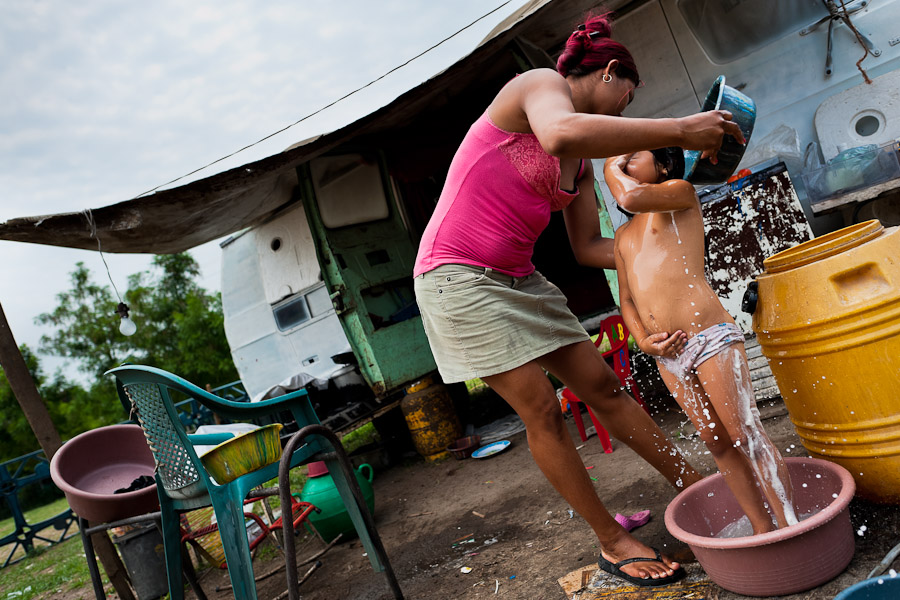 A Salvadorean girl is given a bath in front of the trailer belonged to the Circo Brasilia, a family run circus travelling in Central America.