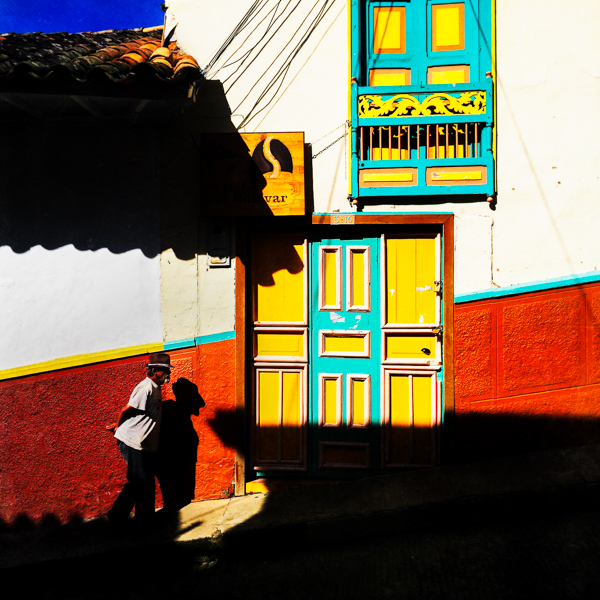 A Colombian peasant walks in front of a brightly painted colonial house in Jericó, a village in the coffee region (Zona cafetera) of Colombia.