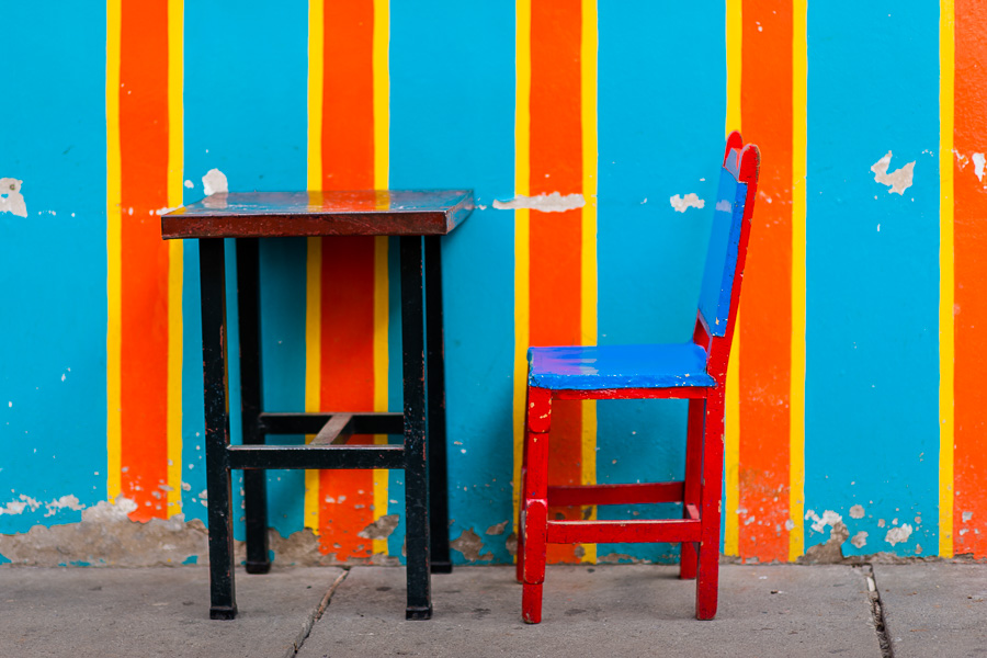 A wooden table with a cowhide chair are seen in front of the brightly paited facade of a colonial house in Jardín, a village in the coffee region of Colombia.