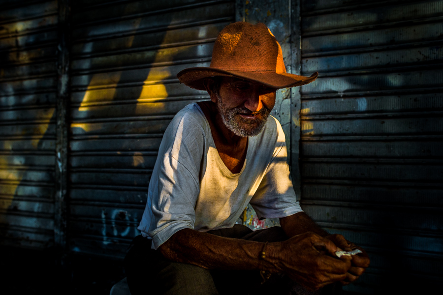 A Colombian shop worker, wearing a cowboy hat, hides in the shadow in Plaza Minorista, a retail market in Medellín, Colombia.