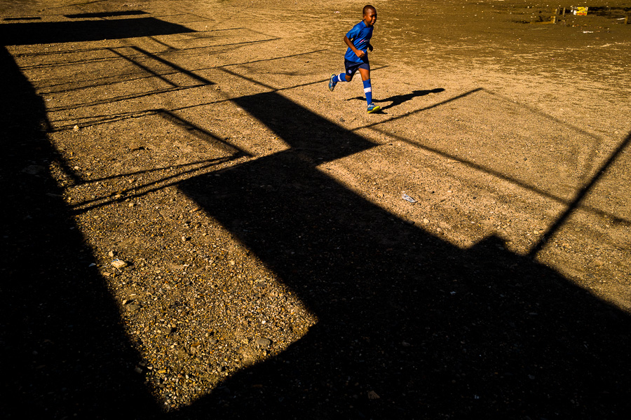 A young Afro-Colombian boy runs during the football training on a dirt playing field in Quibdó, Chocó, Colombia.