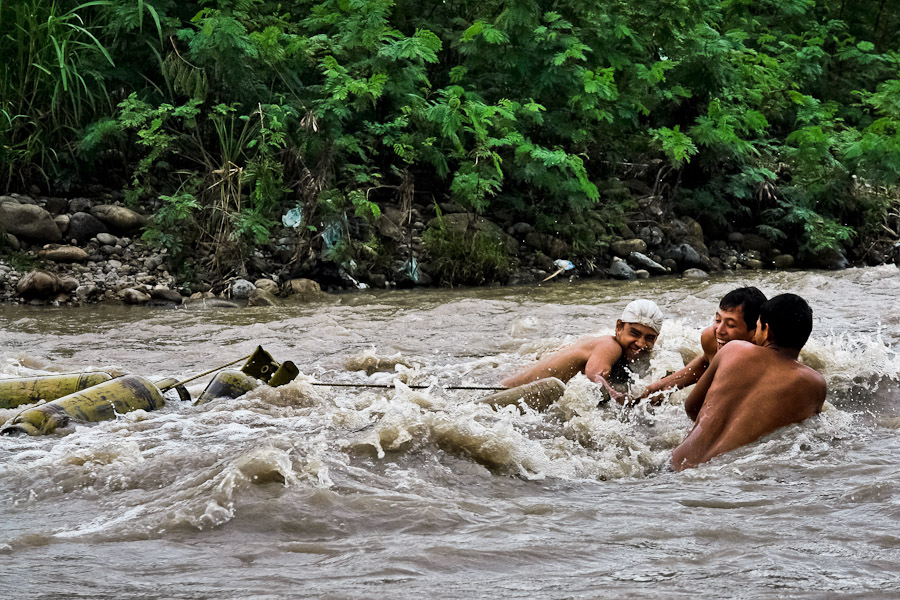 Young Colombian smugglers pulling a rope with gas cylinders tied up on it. They can gain 1-2 USD from one cylinder if they make out the risky journey and sell the contraband in Colombia.