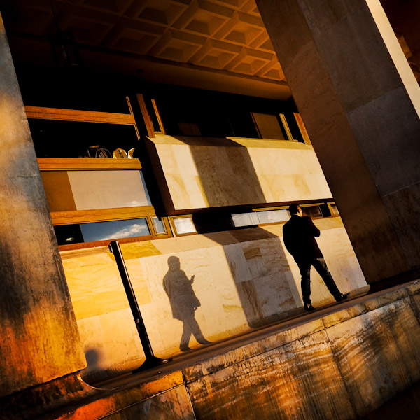 A Colombian man reads a text message while walking along the Congress of the Republic of Colombia during the twilight in Bogotá, Colombia.