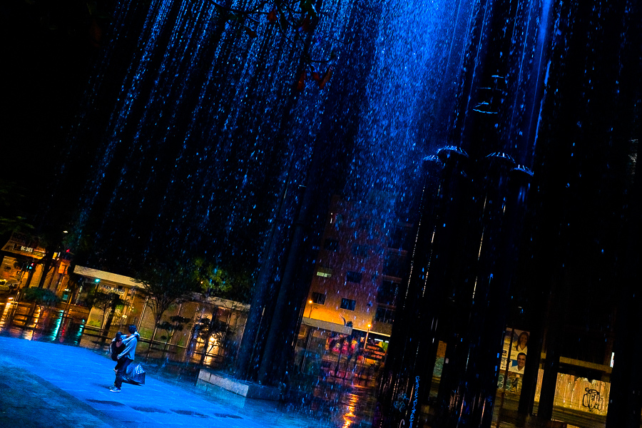 A young Colombian couple play around in the rain curtain waterfall in the Las Chimeneas park in Itagüí, Colombia.