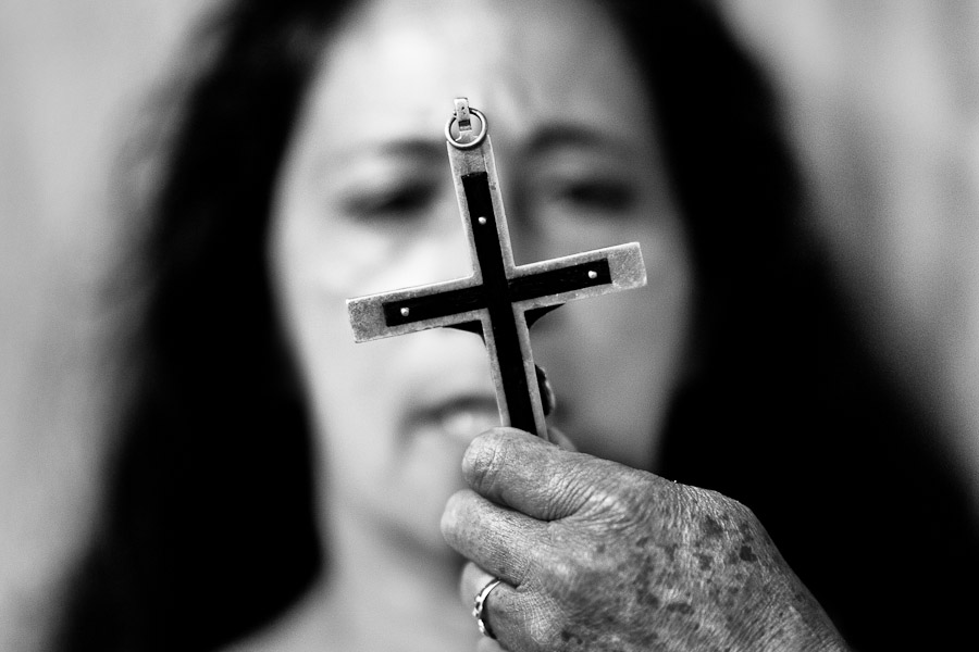 A face of a Colombian woman is seen behind the crucifix during the religious healing ceremony performed at a house church in Bogota, Colombia.