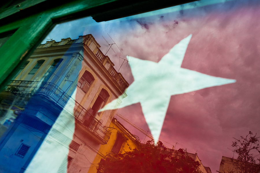 A Cuban national flag is seen reflected in a window on the street of Havana, Cuba.