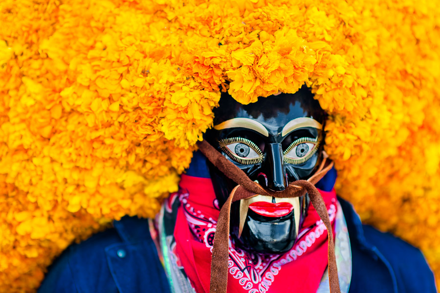 A Mexican man, wearing a black wooden mask with marigold flowers, takes part in the Day of the Dead festivities in Mexico City, Mexico.