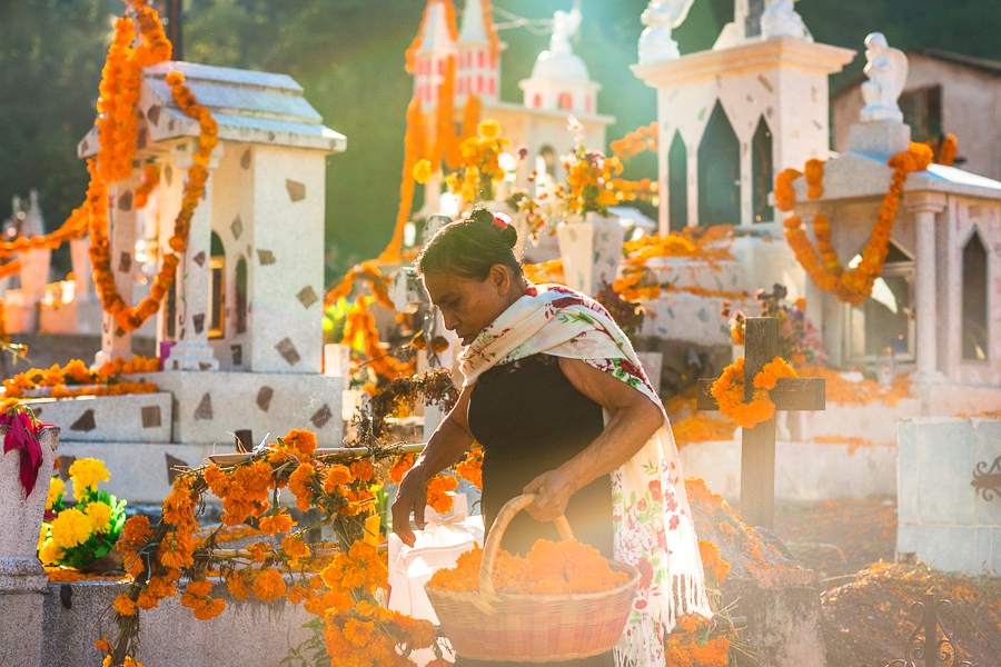 A Mixtec indigenous woman, carrying a basket with marigold flowers, decorates a tomb at a cemetery during the Day of Dead celebrations in Xalpatlahuac, Guerrero, Mexico.
