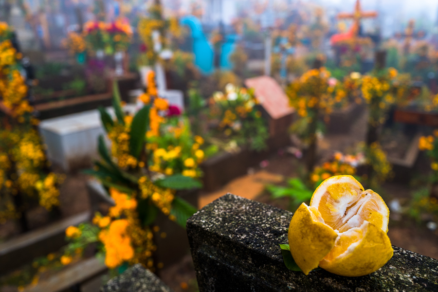A fruit offering is seen placed on a stone cross amongst the flower-decorated graves at a cemetery during the Day of the Dead celebrations in Ayutla, Mexico.