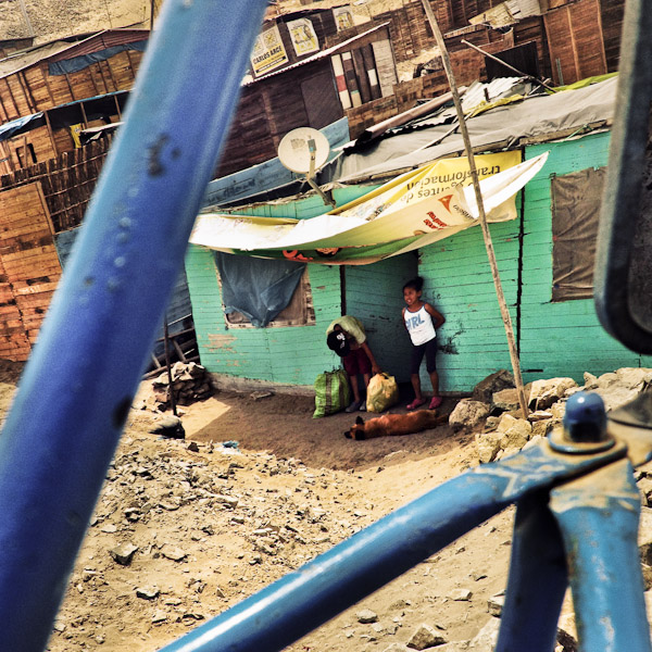 Peruvian family members stand in front of a wooden house built on the dusty hillside of Pachacútec, a desert shantytown in Lima, Peru.