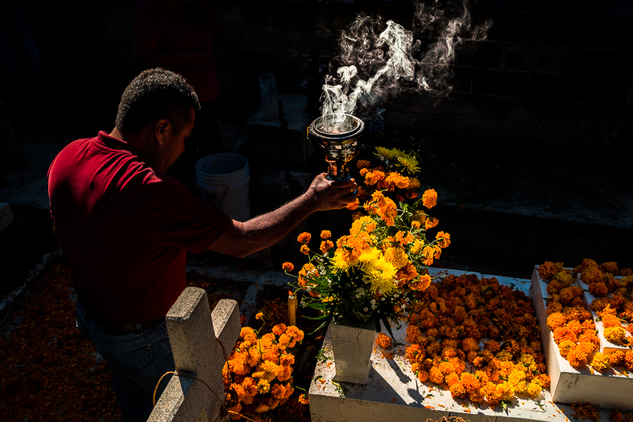 A Mexican man, holding a smoking incense burner, performs a ceremonial purification of a tomb during the Day of Dead celebrations in Tlapa de Comonfort, Guerrero, Mexico.